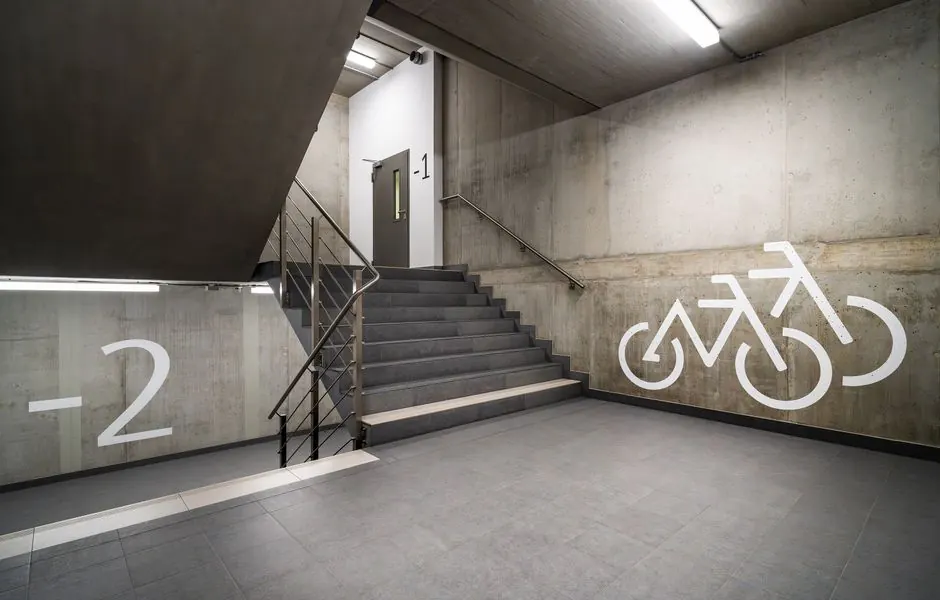 Explore a modern concrete stairway leading to underground bicycle parking, with industrial railings in Poznań.