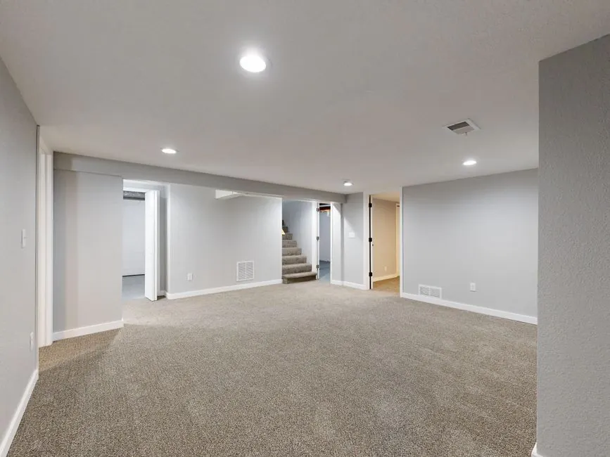 Spacious modern basement with neutral design and carpet flooring, perfect for renovation or real estate listings.